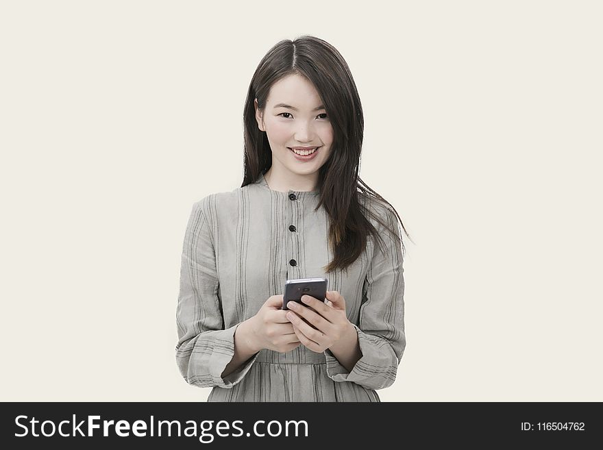 Woman in Gray Button-up Long-sleeved Dress Holding Black Smartphone