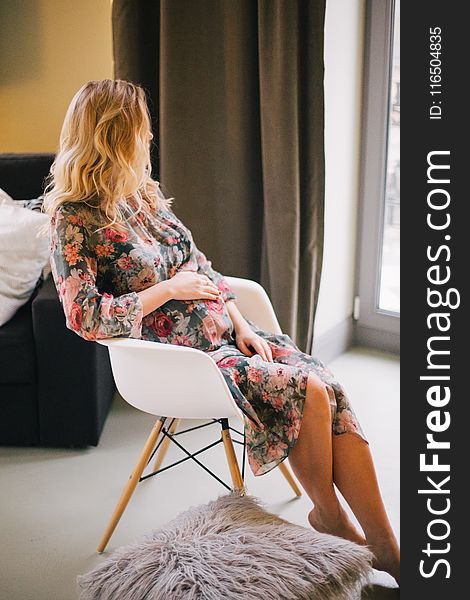 Pregnant Woman Sitting On Armchair Holding Her Tummy