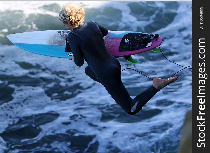 Woman With Surfboard Jumping to Body of Water