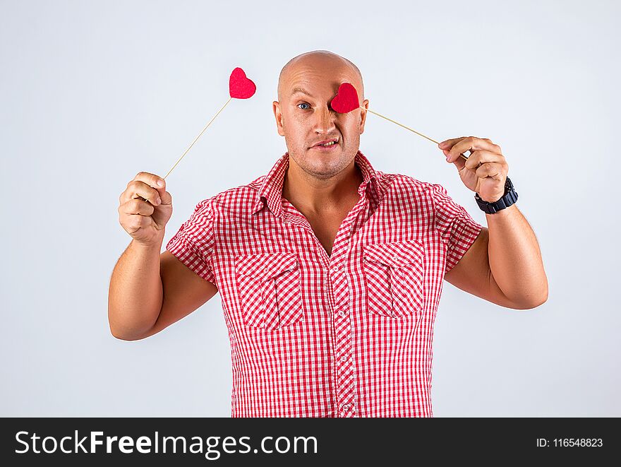 Cheerful man in a shirt on a white background holding hearts, a postcard for Valentine`s day