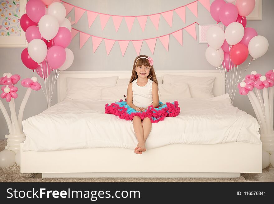 Cute Girl Sitting On Bed In Room Decorated