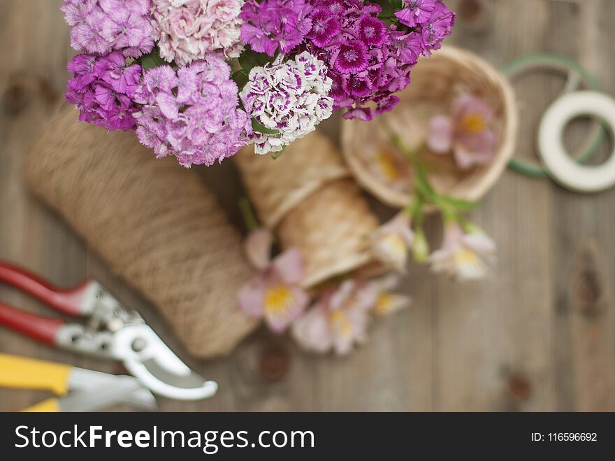 Floristic tools Background. Pink Alstromeria Carnation Flowers on Wooden Background with Garden Floristic Tools and Wire Rustic Floral Board.