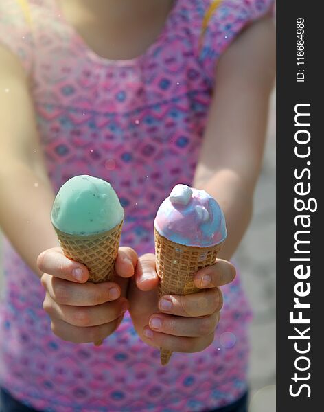 Little Pretty Girls Holding Two Ice Cream cones in Hands. Green Blue Ice Cream Cones. Summer time.