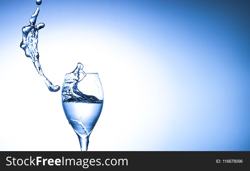 Water splashing out of falling glass on blue background with copy space.