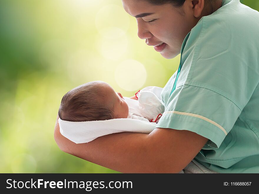 Mother holding newborn infant baby girl in arm on blurred bokeh