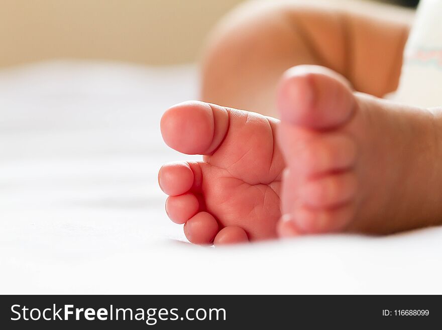 Newborn baby infant feet on white bed, soft tone selective focus