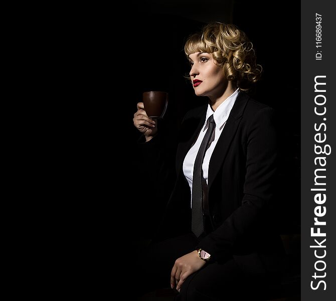 Businesswoman With Cup Of Coffee On A Dark Background. Girl In A Business Suit. Free Space For Your Text