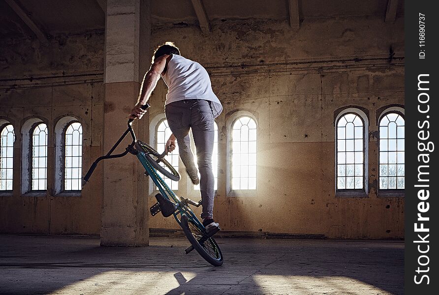 BMX Stunt And Jump Riding In A Hall With Sunlight.