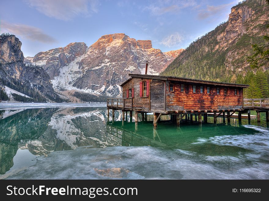 Shack On Body Of Water Surrounded By Mountains