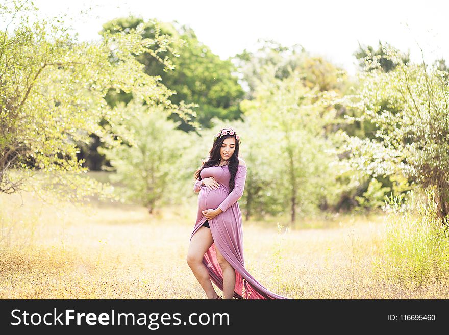 Woman Standing On Grass Field Surrounded With Trees