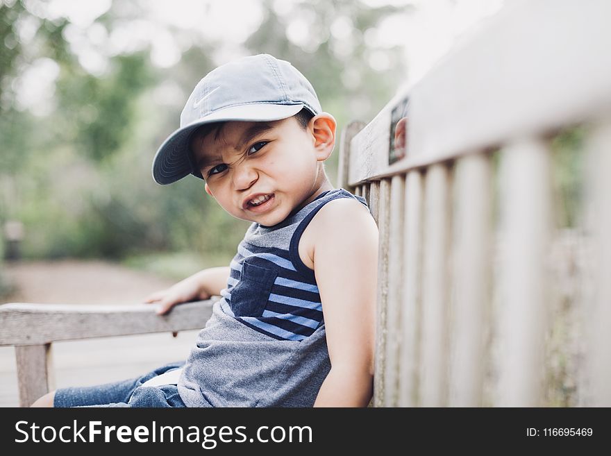 Shallow Focus Photography Of A Boy Sitting On Bench