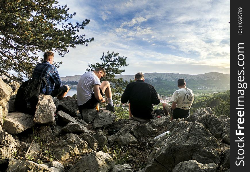 Four Men Seated on Rocks Facing Mountain