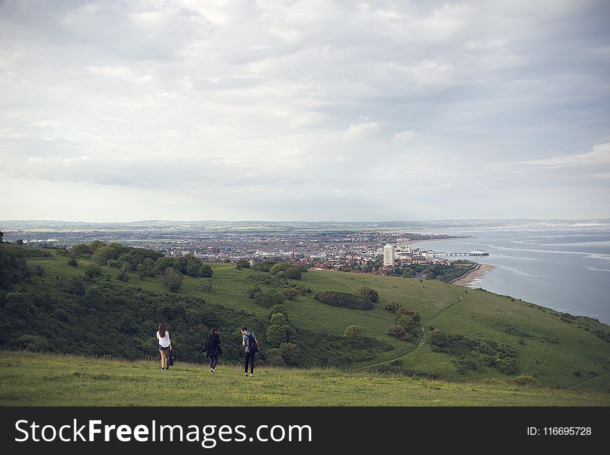 Three People Standing On Grassfield