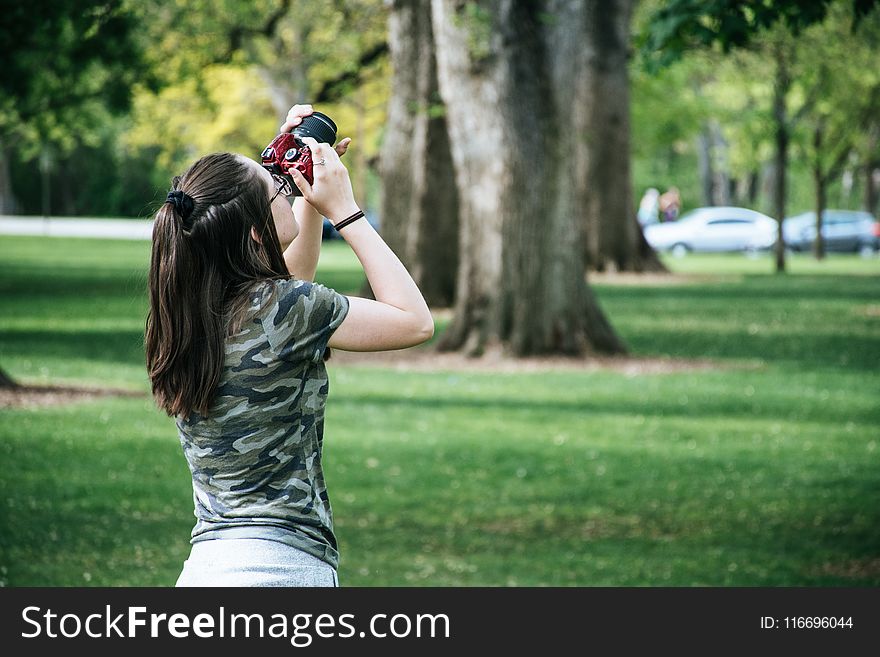 Woman Holding Maroon And Black Camera Facing Upwards