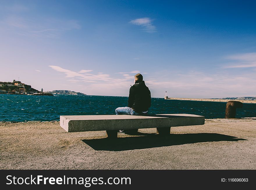 Person Wearing Blue Jeans Sitting on Bench