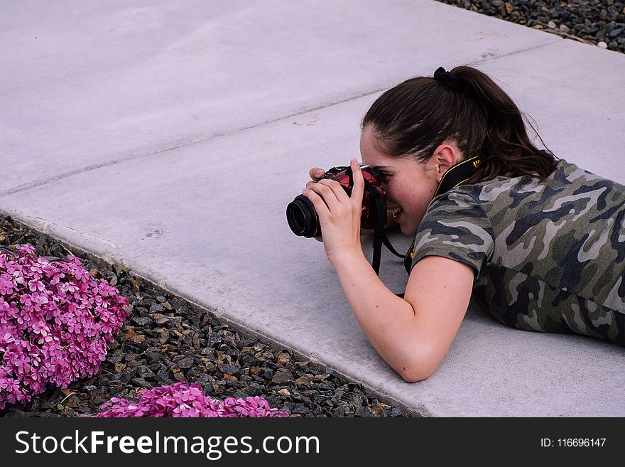Woman Lying on Pavement While Taking Photo