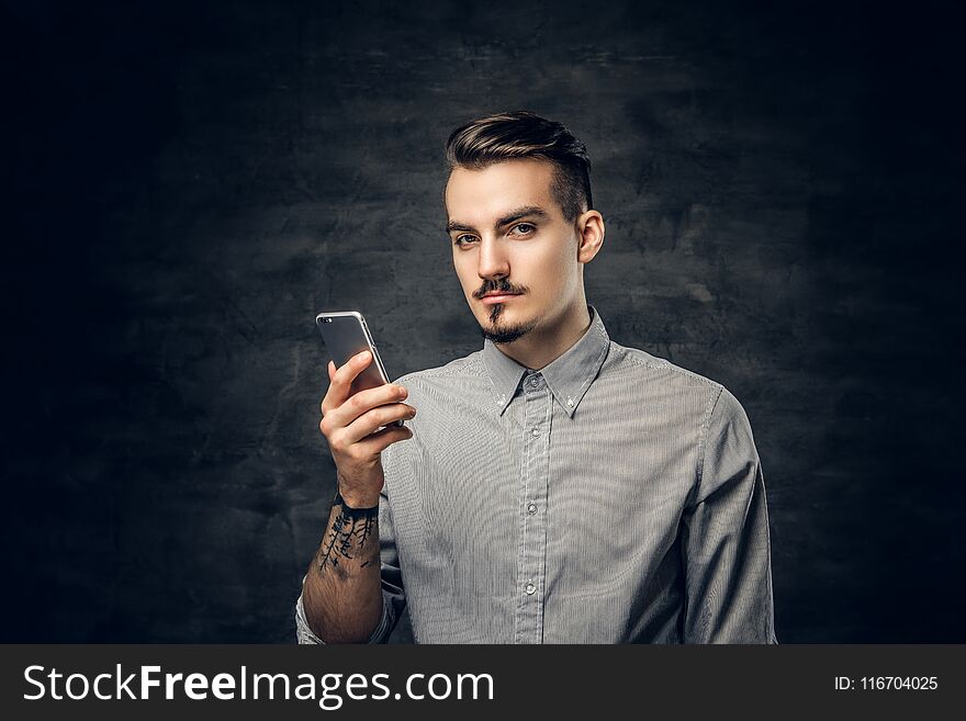 Studio portrait of handsome bearded hipster male with a tattoo on his arm using a smartphone. Studio portrait of handsome bearded hipster male with a tattoo on his arm using a smartphone.