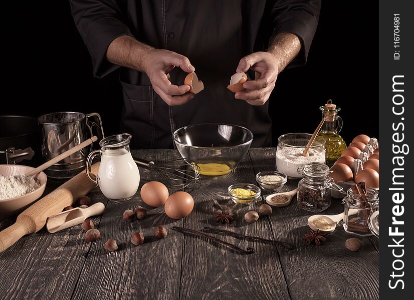 Hands Baker break eggs in glass bowl isolated on black background