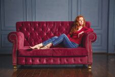 Young Rich Woman Lying On Red Couch Royalty Free Stock Photography