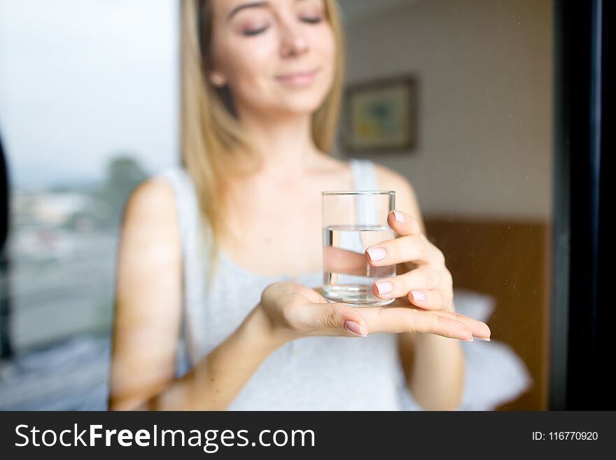 Girl keeping glass of water, blurred background.