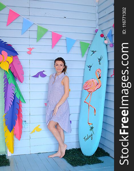 Young Pretty Pregnant Woman Standing Near Surfboard And Decorated Children House.