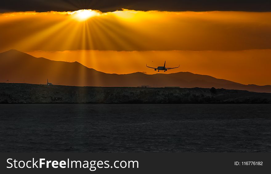 Silhouette Of Airplane Over Body Of Water