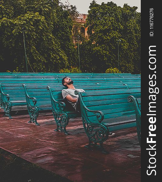 Man Sitting and Closing Eyes on Teal Bench