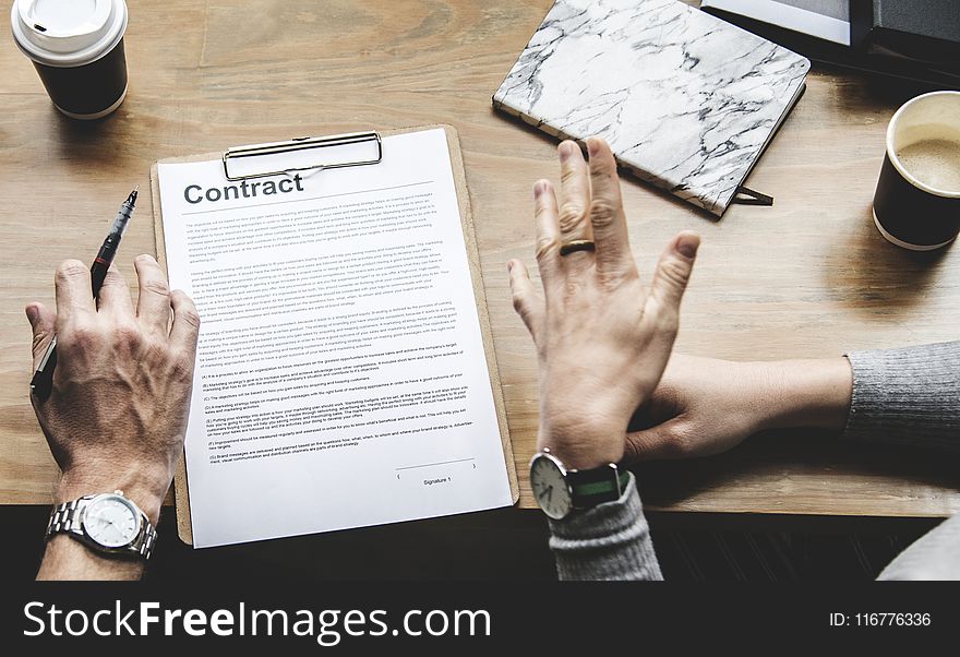 Person Holding Pen in Front Of Contract