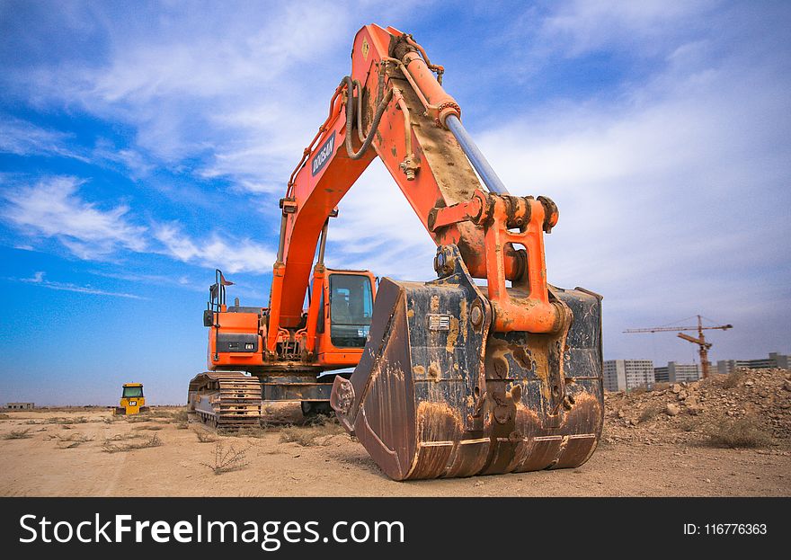 Low Angle Photography of Orange Excavator Under White Clouds