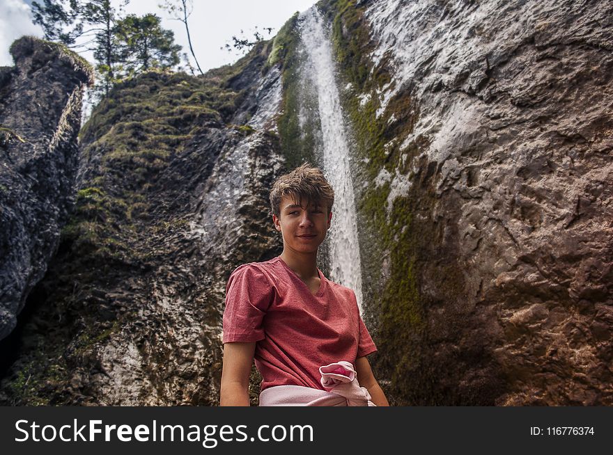 Man Wearing Red Crew-neck Shirt Standing Near Waterfalls