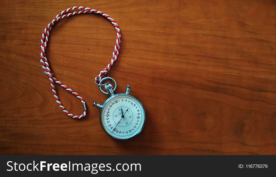 Round Silver-colored Analog Stopwatch on Brown Wooden Panel