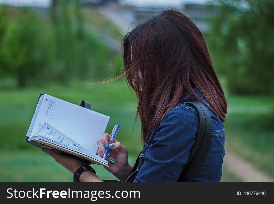 Close-Up Photography Of A Person Writing On Notebook