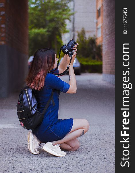 Photography of a Woman Kneeling While Taking a Picture