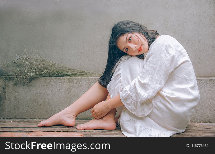 Woman Wearing White Dress Sitting On Wooden Floor