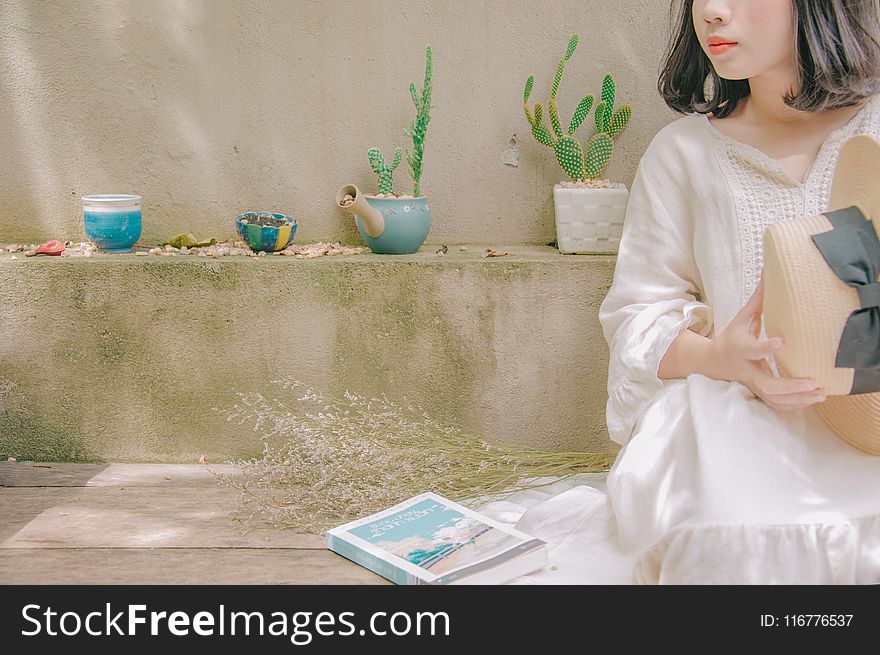 Photography Of Woman Sitting Holding Straw Hat