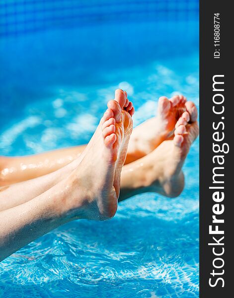 Two pairs of Female feet splashing in the pool, water splashing.