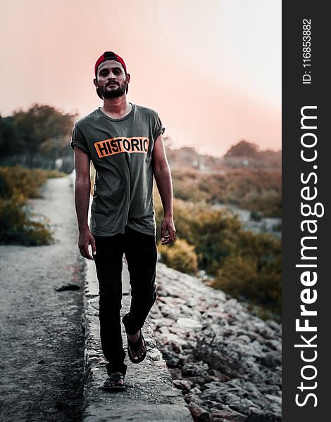 Man In Gray Shirt Standing On Concrete Pathway