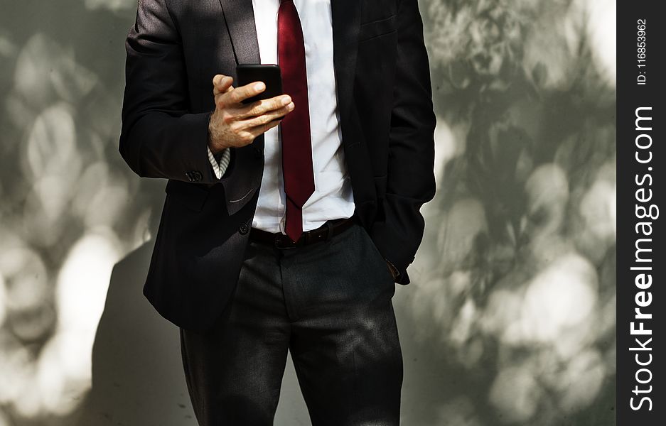Man Wearing Black Tuxedo Holding Black Smartphone