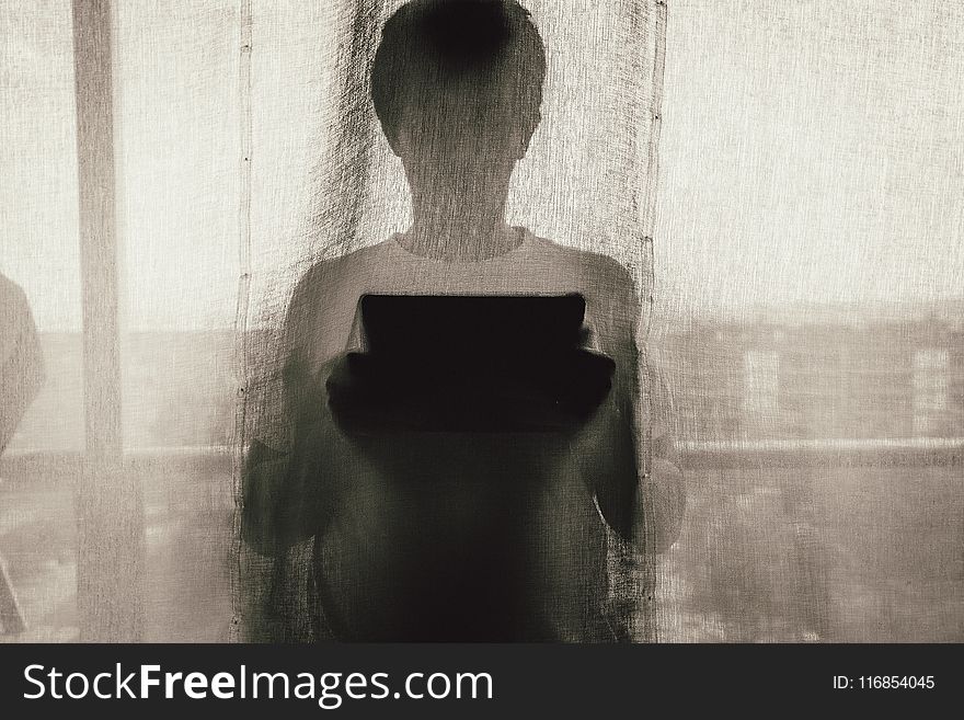 Man Standing Holding A Tablet Behind Curtain