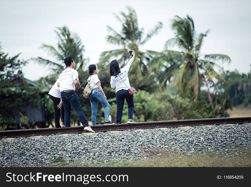 Person Taking A Selfie With Three Persons On Train Railway