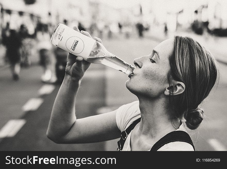 Woman Holding Glass Bottle in Grayscale Photo