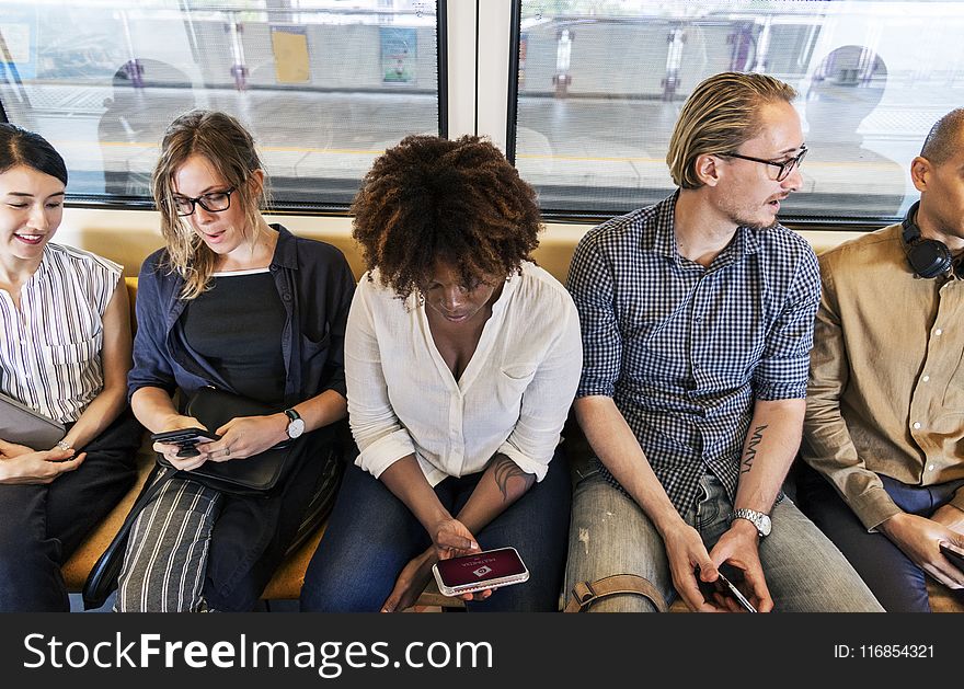Woman Sitting Holding Smartphone Between Two Men and Two Women