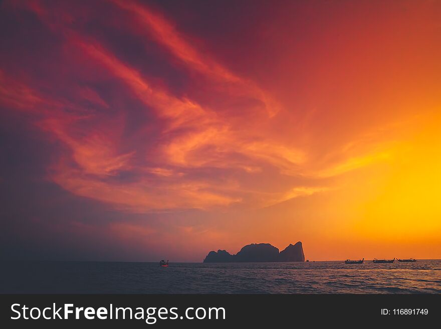 Spectacular sunset over the Indian Ocean next to the exotic Phi Phi Islands in the Kingdom of Thailand. Amazing golden and scarlet color combination. Perfect background. Spectacular sunset over the Indian Ocean next to the exotic Phi Phi Islands in the Kingdom of Thailand. Amazing golden and scarlet color combination. Perfect background.