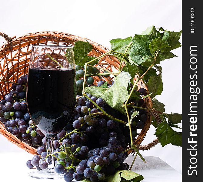 Ripe harvested Grapes in a basket with a glass of wine