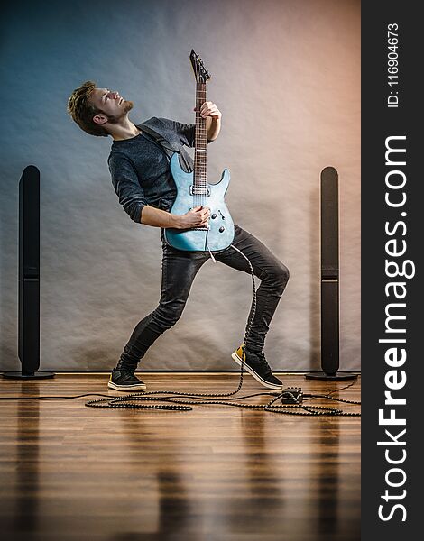 Young bearded man with electric guitar. Adult person in full length is holding instrument and playing. Hobby, music concept, on grey. Young bearded man with electric guitar. Adult person in full length is holding instrument and playing. Hobby, music concept, on grey