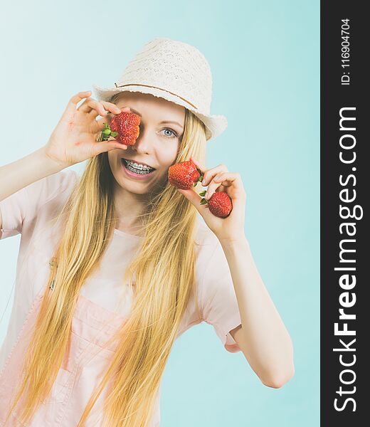 Young positive woman playing with fresh strawberries fruits, on blue. Healthy meal. Young positive woman playing with fresh strawberries fruits, on blue. Healthy meal.