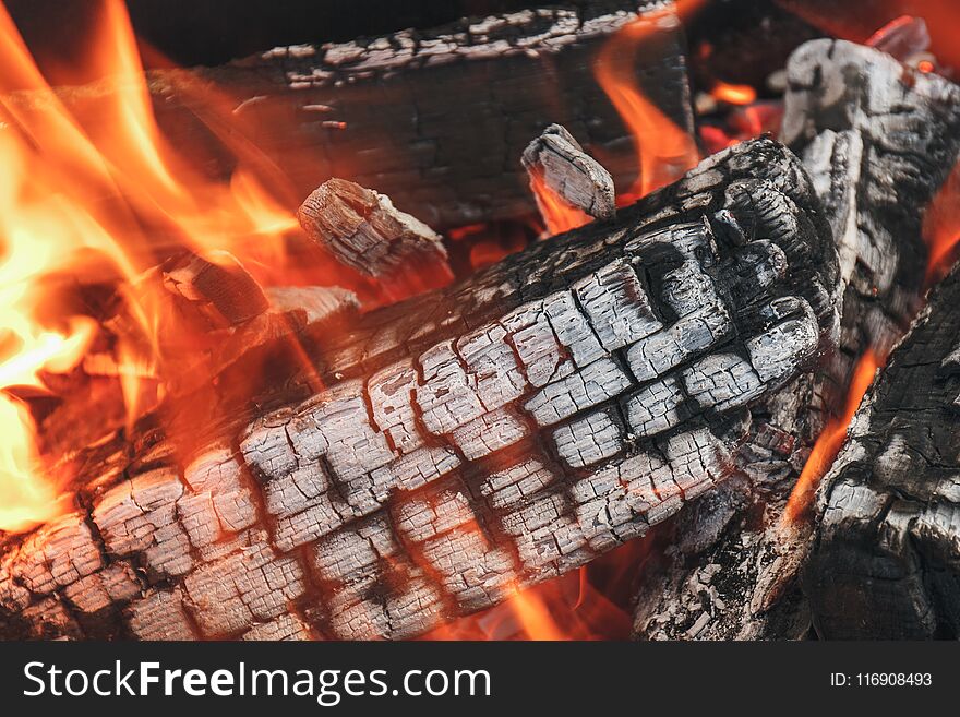 Wooden logs in a campfire with smoke and flame. Natural fire of firewood background.