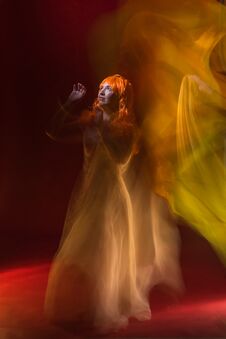 Old Female Actress With Orange Hair Dancing In White Dress With Light Show With Yellow, Orange And Green Lights Around Stock Photos