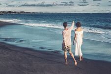 Couple Walking On Beach. Young Happy Couple Walking On Beach Smiling Holding Around Each Other. Stock Photo