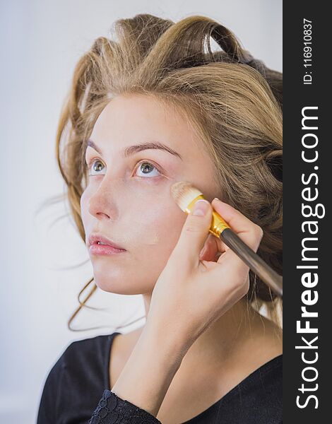 Makeup artist applying liquid tonal foundation on the face of the woman